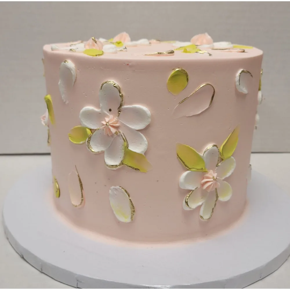 A pale pink cake decorated with painted petals